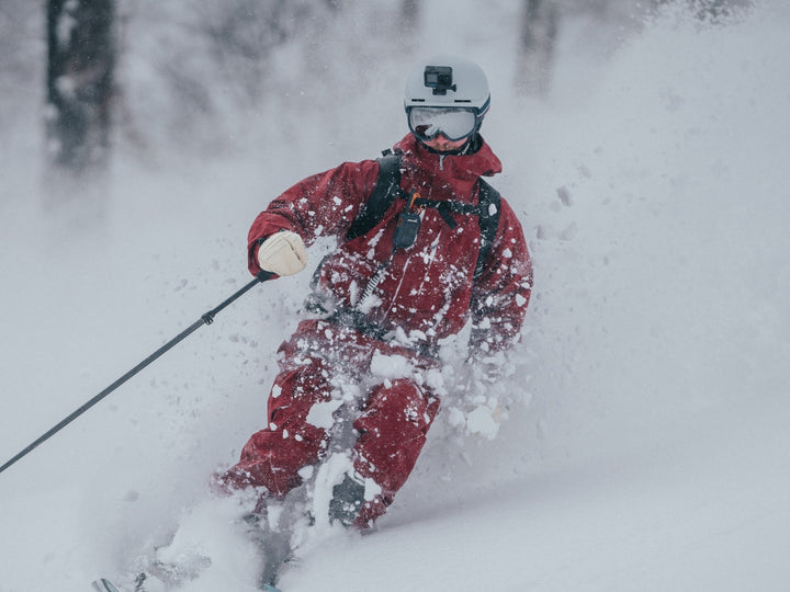 Man wears VALLON Freebirds goggles while skiing in powder on an overcast day