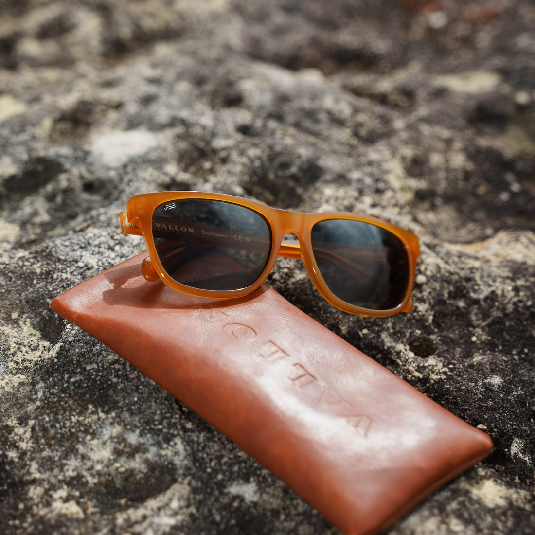 Pair of Megos Edition Daytrippers from VALLON on a brown leather pouch sitting on a rock