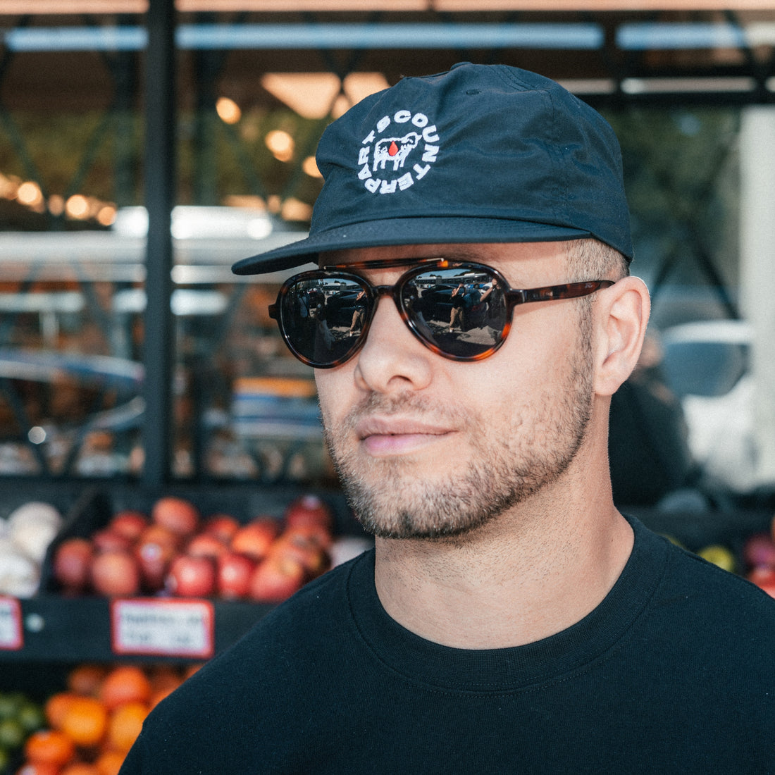 Man wears Elmore brow-bar aviator sunglasses with classic 80s style in front of a city grocery store