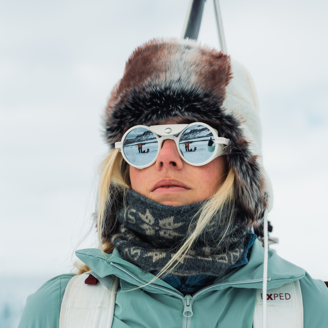 A woman wears VALLON Heron Glacier white sunglasses with Cat. 4 lenses for a glacier expedition to Svalbard
