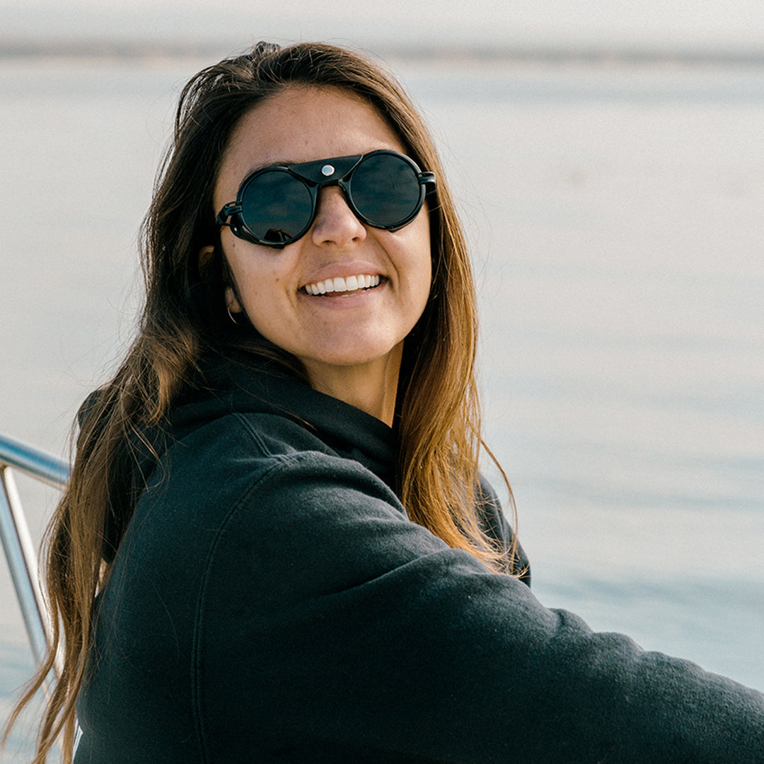 Woman wears Heron Ocean polarized side shield sunglasses from VALLON for sailing