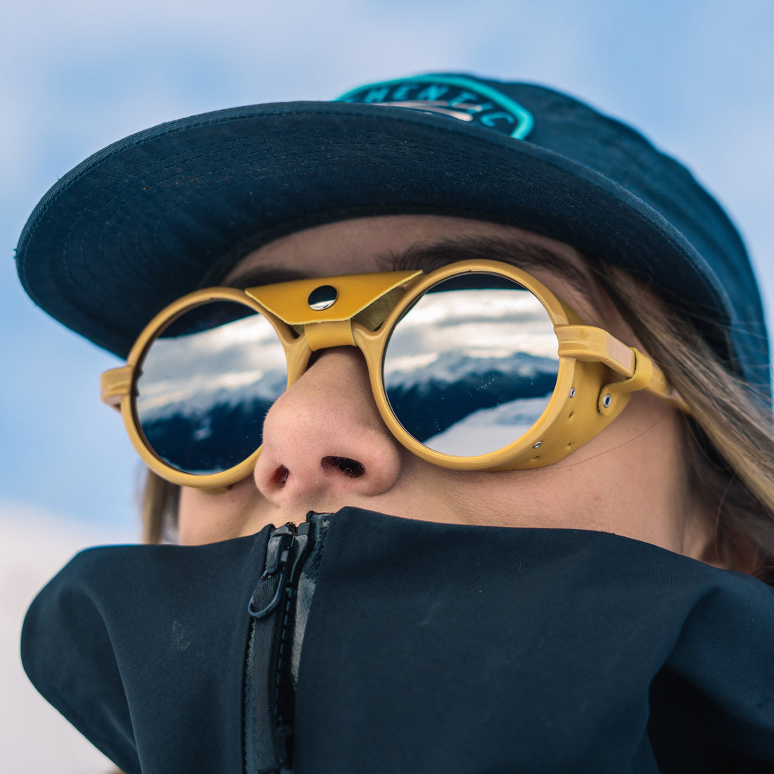 Woman wears yellow Heron Glacier glasses from VALLON with full mirror lenses