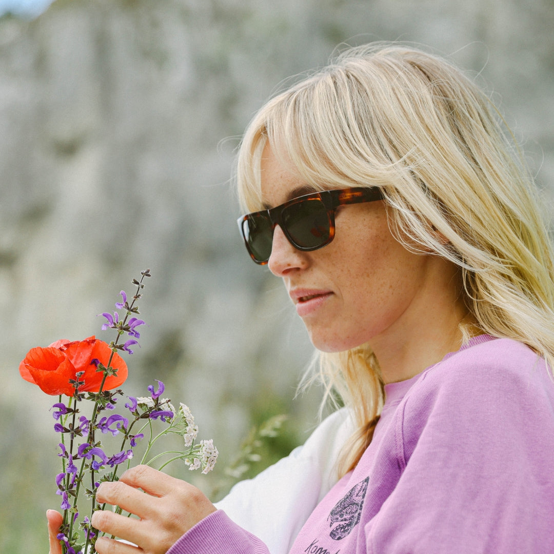 Woman wears June sunglasses from VALLON while picking wild flowers