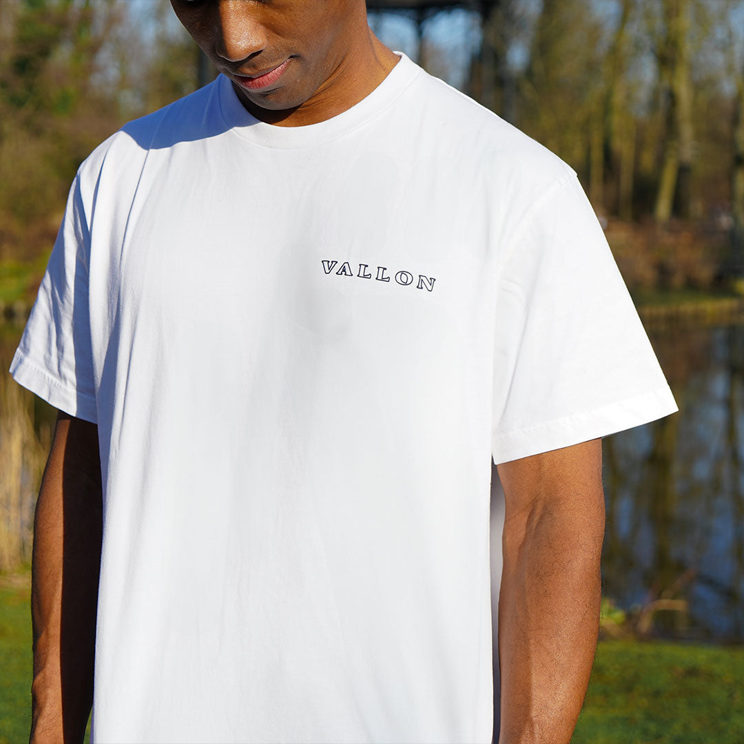 Person wearing a white t-shirt with 'Vallon' logo outdoors