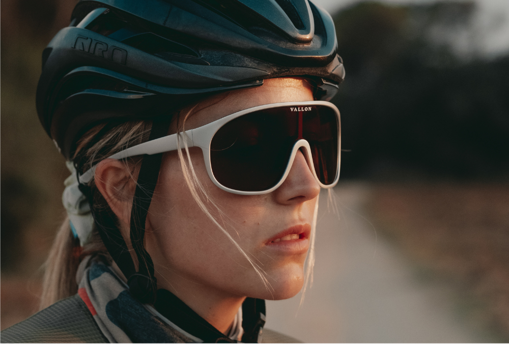 A female cyclist wears Watchtowers sunglasses made with ZEISS lens tech from VALLON