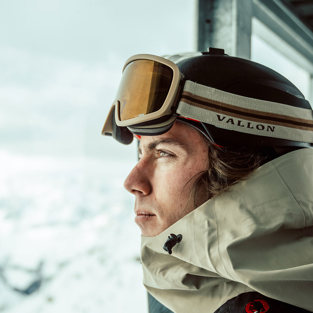 Man wears Stairways retro-inspired ski goggles looking out at mountains